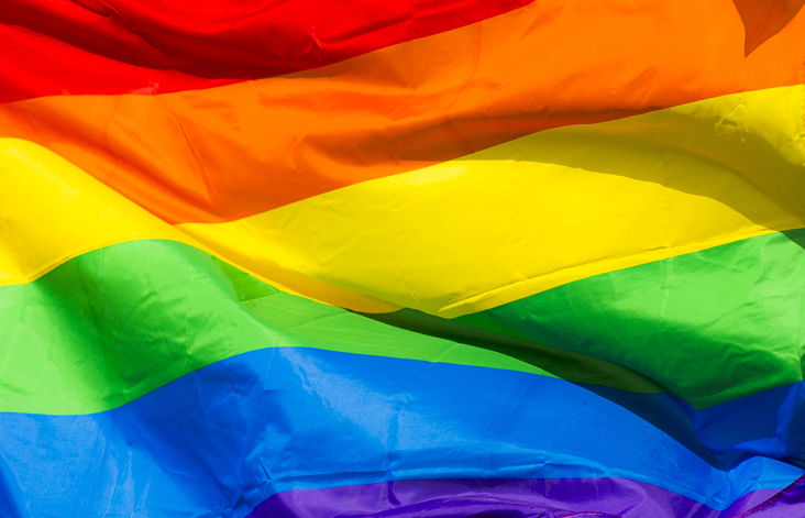 A close-up of a rainbow Pride flag moving in the wind.