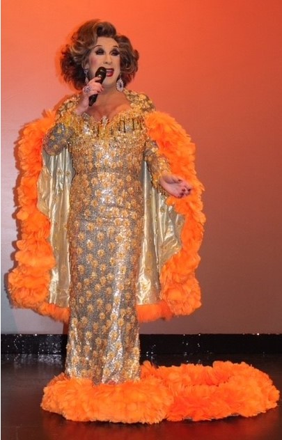 Ceri Dupree singing in a gold dress with orange feather trim