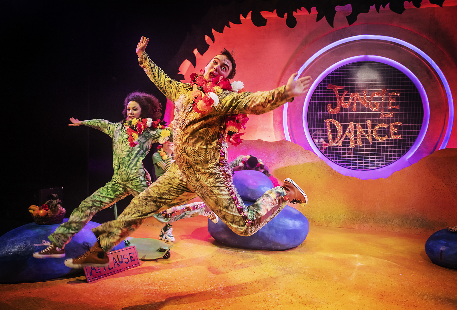 A production image from Giraffes Can't Dance showing two Jungle Friends leaping excitedly into the air wearing camo print boiler suits.