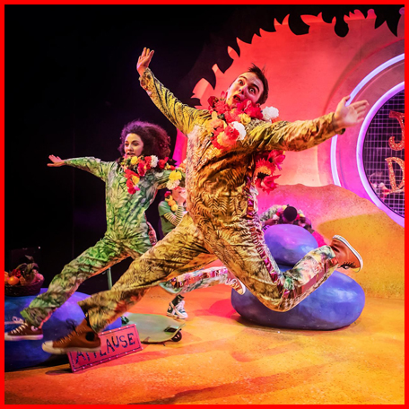 A production image from Giraffes Can't Dance showing two Jungle Friends leaping excitedly into the air wearing camo print boiler suits.