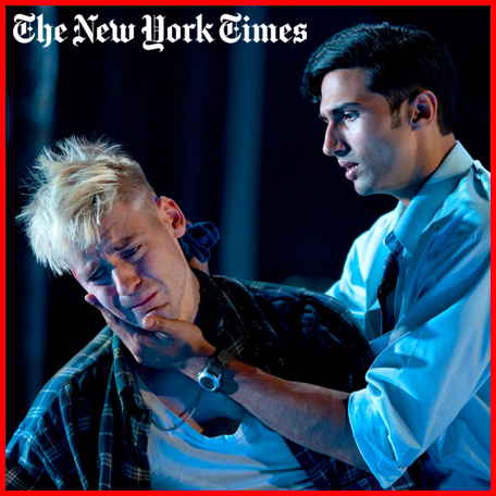 Production image from My Beautiful Laundrette. Omar (Omar Malik) holds Johnny's (Jonny Fines) face as he looks away forlorn on a blue stage. White The New York Times logo top left.